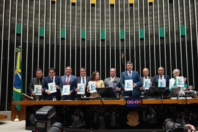 FIESC defende prioridades da indústria no Congresso Presidentes de federações industriais, incluindo Gilberto Seleme da FIESC e Ricardo Alban da CNI, posam no Plenário da Câmara dos Deputados em Brasília durante o lançamento oficial da 31ª Agenda Legislativa da Indústria, segurando cópias do documento que delineia as prioridades do setor industrial brasileiro para políticas públicas.