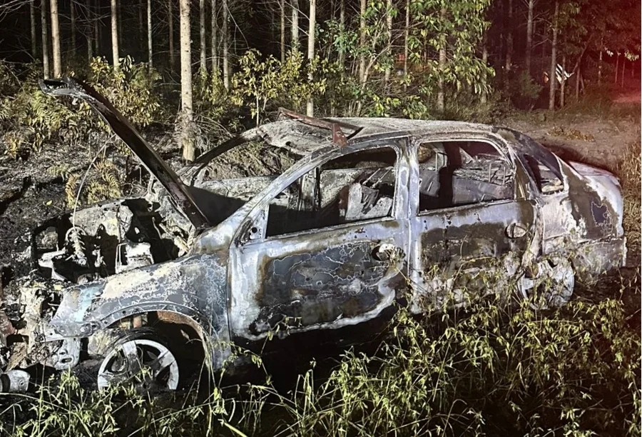 Fogo em carro atinge área de reflorestamento na Gaivota Carro totalmente carbonizado após incêndio em Balneário Gaivota, Santa Catarina. A imagem mostra o veículo destruído em uma estrada de terra ao lado de uma área de reflorestamento atingida pelo fogo durante a noite.