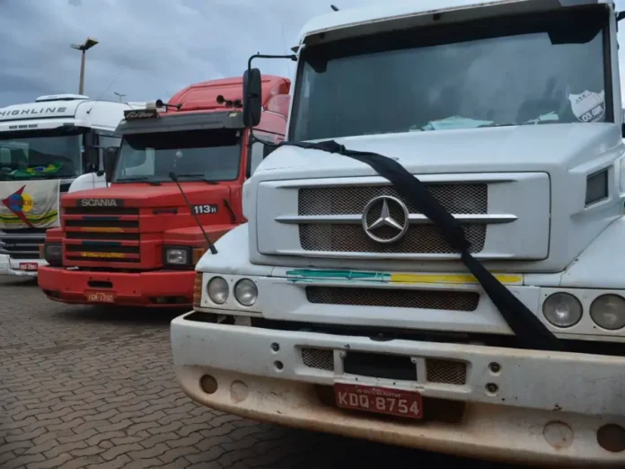 Governo ameaça suspender empresas por descumprir frete Fila de caminhões parados em rodovia brasileira durante o dia, ilustrando a logística de transporte de cargas e a mobilização de caminhoneiros contra a alta do diesel.