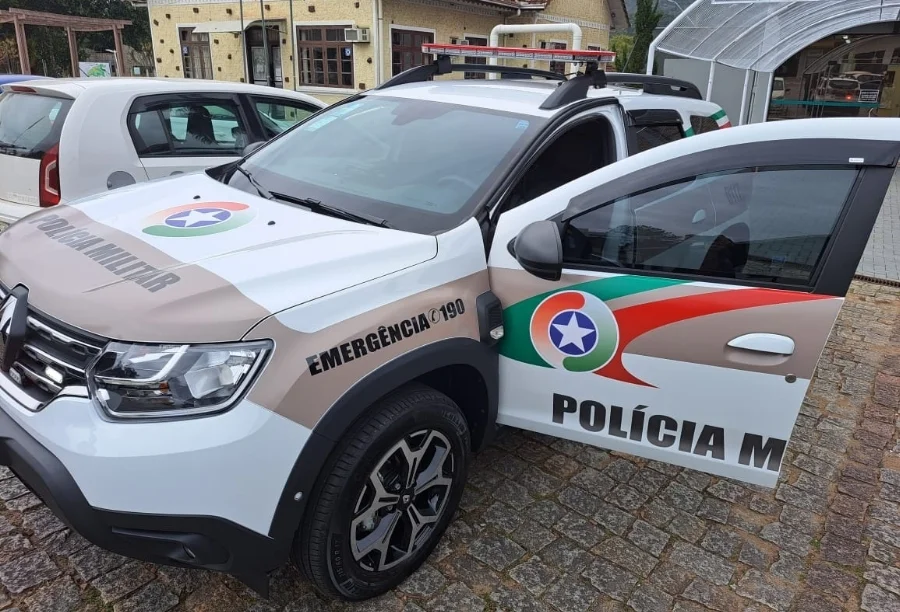 Viatura da Polícia Militar de Santa Catarina (PMSC), modelo Renault Duster, estacionada durante operação policial em Orleans. O veículo oficial apresenta as cores branco, marrom e verde, com o giroflex e adesivos de emergência 190 visíveis em primeiro plano.