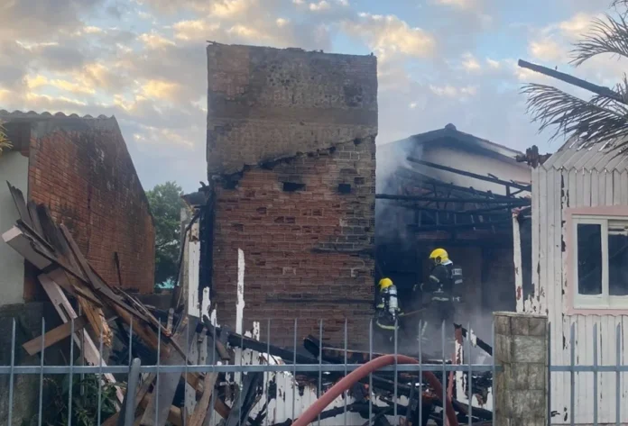 Incêndio destrói casa no bairro Mato Alto em Araranguá Dois bombeiros do CBMSC combatem incêndio em residência no bairro Mato Alto, em Araranguá, SC, entre escombros e paredes de tijolos carbonizados. Foto mostra destruição da casa após o fogo.
