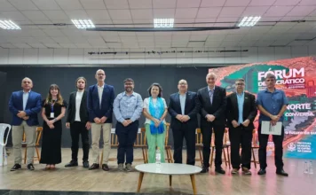 Litoral Norte do RS debate infraestrutura e novos investimentos Um grupo de dez pessoas em pé no palco durante o painel de discussão do Fórum Democrático da Assembleia Legislativa do Rio Grande do Sul (ALRS) na Casa de Cultura Érico Veríssimo, em Capão da Canoa. O banner ao fundo tem a inscrição "FÓRUM DEMOCRÁTICO" e discute o desenvolvimento regional do Litoral Norte gaúcho, abordando temas de infraestrutura como saneamento e energia elétrica. As pessoas estão vestidas formalmente e posam para uma foto oficial do evento.