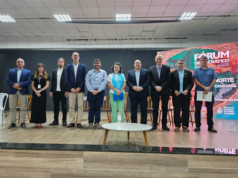 Litoral Norte do RS debate infraestrutura e novos investimentos Um grupo de dez pessoas em pé no palco durante o painel de discussão do Fórum Democrático da Assembleia Legislativa do Rio Grande do Sul (ALRS) na Casa de Cultura Érico Veríssimo, em Capão da Canoa. O banner ao fundo tem a inscrição