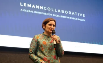 Nobel de Economia defende dados em políticas públicas Esther Duflo, economista ganhadora do Prêmio Nobel, palestrando no palco de um evento sobre políticas públicas da Fundação Lemann e Enap em Brasília. Ela segura um microfone e está na frente de uma tela azul com o texto projetado 'LEMANN COLLABORATIVE: A GLOBAL INITIATIVE FOR EXCELLENCE IN PUBLIC POLICY'.