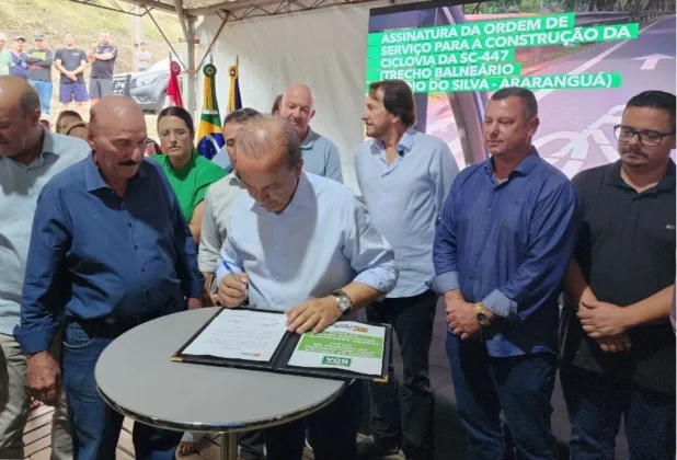 Governador Jorginho Mello assina documento oficial de investimento em infraestrutura cercado por autoridades em Ararangu&aacute;.