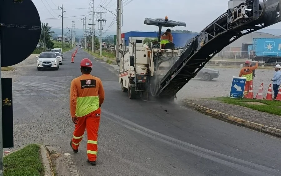 Obras na Avenida Kleinubing alteram trânsito em Cocal do Sul Fresa de asfalto em operação na Avenida Kleinubing em Cocal do Sul para obra de recuperação da via. Operário de uniforme laranja caminha na pista próxima à máquina e a cones de sinalização.