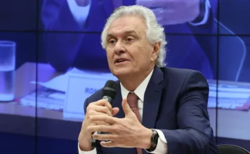 PSD oficializa Caiado como pré-candidato à Presidência O governador de Goiás, Ronaldo Caiado, falando ao microfone durante evento político. Ele veste terno azul escuro e gravata bordô, gesticulando com a mão em um ambiente de conferência.