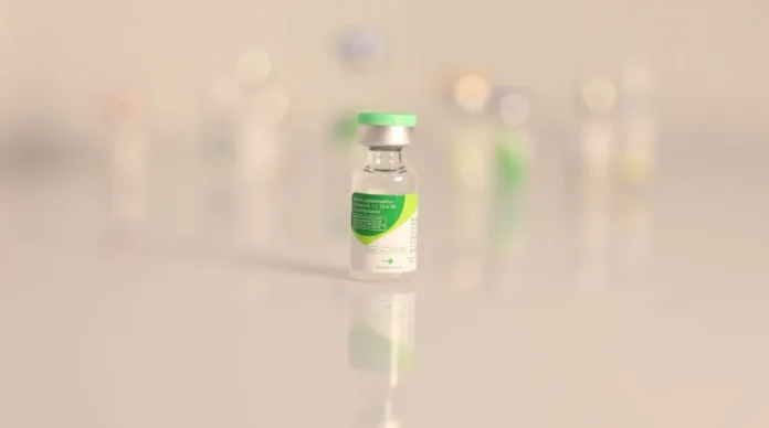 SC alerta para prevenção do câncer de colo do útero Frasco da vacina contra o HPV (Papilomavírus Humano) em destaque sobre superfície clara e refletora, simbolizando a imunização e prevenção do câncer de colo do útero em Santa Catarina.