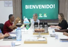 Unesc e universidade colombiana discutem parcerias Reunião na Unesc, em Criciúma, com a reitora em exercício Gisele Silveira Coelho Lopes e o professor Alexis Calabari Angola da Universidad de La Guajira, Colômbia. Na mesa, pequenas bandeiras do Brasil e da Colômbia, garrafas de café e um bolo. Ao fundo, uma tela exibe a mensagem "BIENVENIDO!" com o logotipo da Unesc, marcando o início da visita institucional para parcerias acadêmicas e internacionalização.