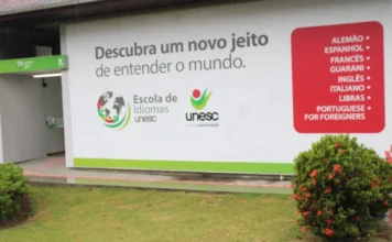 Unesc sedia evento inédito sobre ensino de idiomas Fachada da Escola de Idiomas da Unesc em Criciúma com painel exibindo a lista de cursos oferecidos, local que sedia o evento de formação para professores BRAZ-TESOL Santa Catarina.
