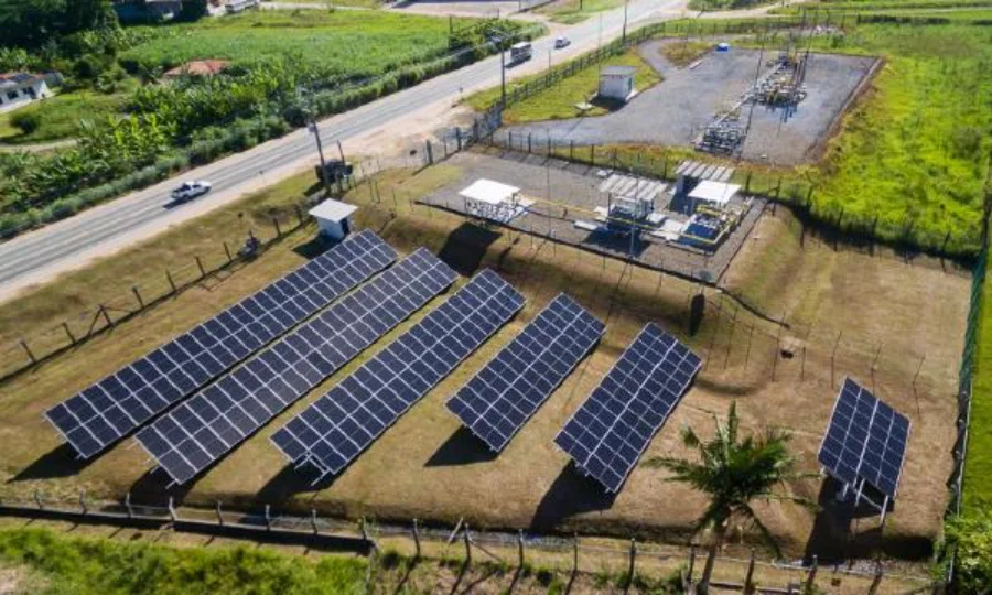 Usina solar da SCGÁS reduz custos em mais de R$ 112 mil Vista aérea da usina solar da SCGÁS em Santa Catarina, com fileiras de painéis fotovoltaicos instalados em área gramada próxima a infraestrutura de gás natural para geração de energia limpa e descarbonização.