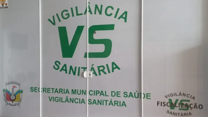 Vigilância de Cocal do Sul alerta para golpe contra comércio Identificação visual da Vigilância Sanitária e Secretaria Municipal de Saúde na fachada de vidro do órgão público em Cocal do Sul, Santa Catarina.