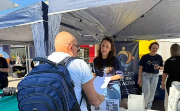 ACIVA realiza primeiro Feirão do Emprego em Araranguá Candidato com mochila azul conversa com recrutadora no stand do Núcleo de RH da ACIVA durante o primeiro Feirão do Emprego no Calçadão de Araranguá. Sobre a mesa, formulários impressos e QR code para cadastro de currículos em evento de empregabilidade.