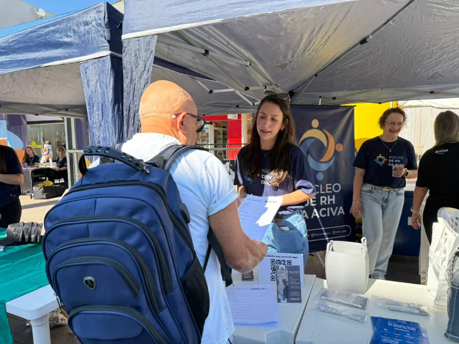 ACIVA realiza primeiro Feirão do Emprego em Araranguá Candidato com mochila azul conversa com recrutadora no stand do Núcleo de RH da ACIVA durante o primeiro Feirão do Emprego no Calçadão de Araranguá. Sobre a mesa, formulários impressos e QR code para cadastro de currículos em evento de empregabilidade.