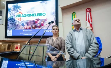 Agrimeleiro: Comitiva convida Alesc para evento em maio Prefeito de Meleiro, Anderson Scarduelli, e Jovana Peterle na tribuna da Assembleia Legislativa de Santa Catarina (Alesc) apresentando o cartaz digital da 8ª Agrimeleiro no telão ao fundo para divulgação do evento agrícola.