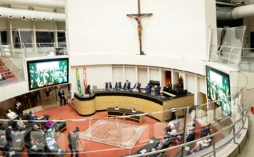 Alesc homenageia 40 anos da Acate em sessão especial Plenário da Assembleia Legislativa de Santa Catarina (Alesc) durante sessão especial em homenagem aos 40 anos da ACATE, em Florianópolis. A imagem mostra a mesa diretiva com autoridades, telas laterais exibindo os participantes e o público presente no evento de tecnologia e inovação.