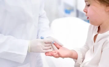 Anvisa libera Mounjaro para crianças com diabetes tipo 2 Profissional de saúde com luvas realiza teste de glicemia no dedo de uma criança em ambiente clínico, ilustrando o tratamento de diabetes tipo 2 pediátrico após nova regulamentação da Anvisa.