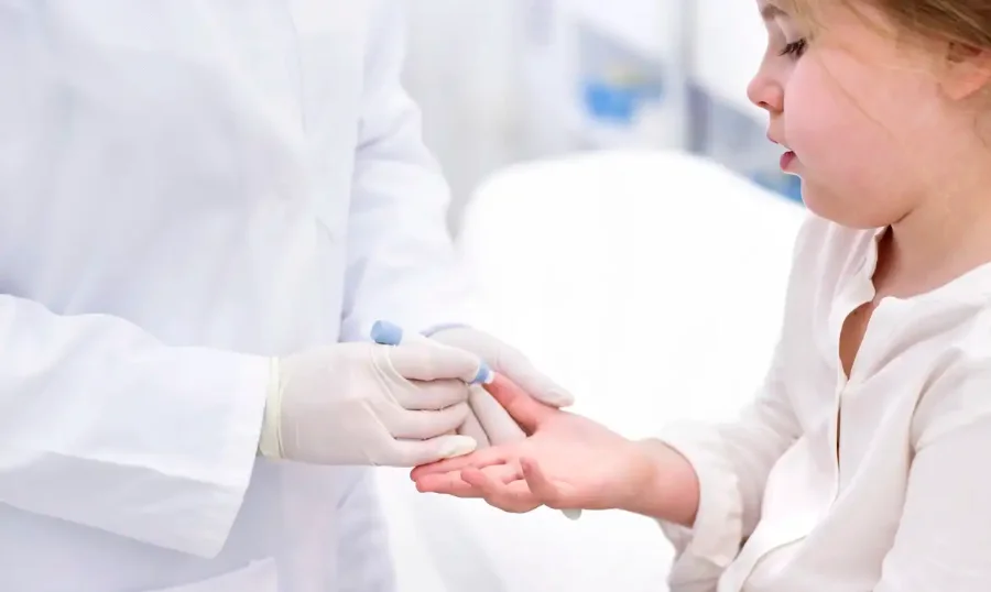 Profissional de saúde com luvas realiza teste de glicemia no dedo de uma criança em ambiente clínico, ilustrando o tratamento de diabetes tipo 2 pediátrico após nova regulamentação da Anvisa.