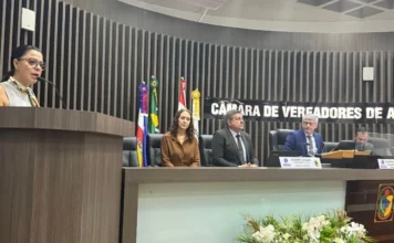 Araranguá abre inscrições para curso superior gratuito Coordenadora do Polo UAB de Araranguá, Maeve Espíndola Pereira, discursa na tribuna da Câmara de Vereadores sobre a abertura de inscrições para o curso gratuito de Administração Pública. A imagem detalha a palestrante em primeiro plano e a mesa diretora do legislativo ao fundo durante a 18ª sessão ordinária.