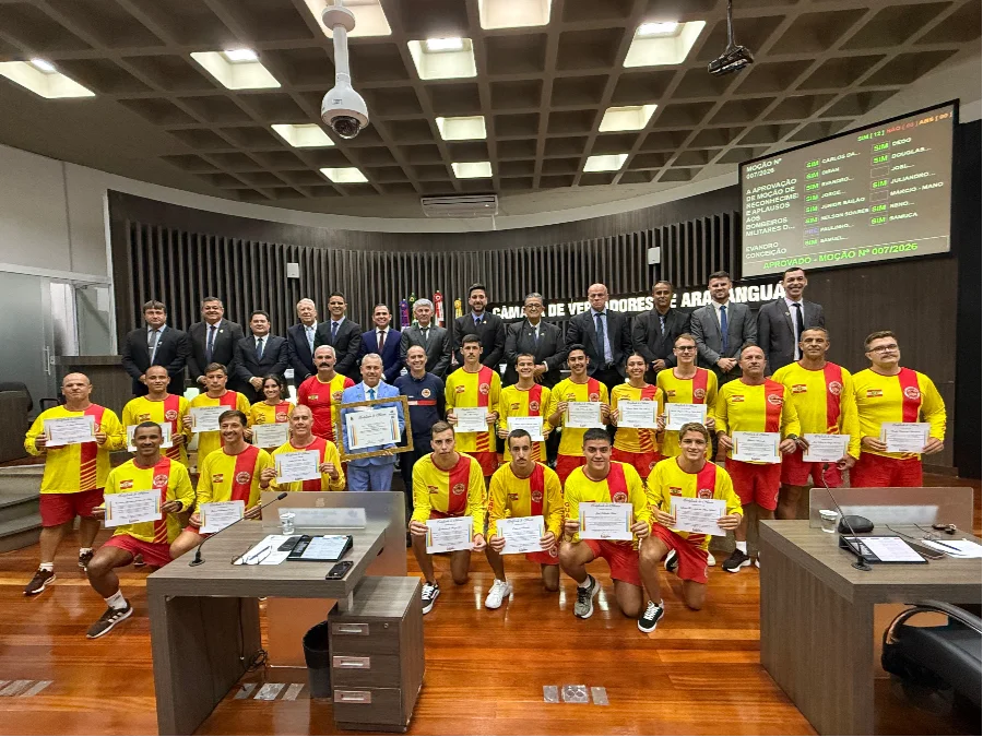 Guarda-vidas civis e militares seguram certificados de Moção de Reconhecimento no plenário da Câmara de Vereadores de Araranguá, posando ao lado de vereadores e autoridades do Corpo de Bombeiros pela atuação na Operação Veraneio 2026 no Morro dos Conventos.
