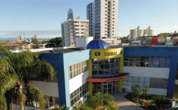 Araranguá faz 146 anos com R$ 31 milhões em saneamento Fachada frontal da sede do SAMAE Araranguá em dia ensolarado. O prédio do Serviço Autônomo Municipal de Água e Esgoto exibe cores azul e amarelo com arquitetura moderna, simbolizando a infraestrutura de saneamento básico e os investimentos hídricos nos 146 anos do município.