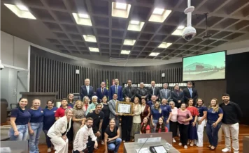 Araranguá homenageia 95 anos da Escola Maria Garcia Pessi Representantes da EEB Professora Maria Garcia Pessi e vereadores de Araranguá reunidos no plenário da Câmara segurando o quadro da Moção de Reconhecimento e Aplausos pelos 95 anos de fundação da escola.