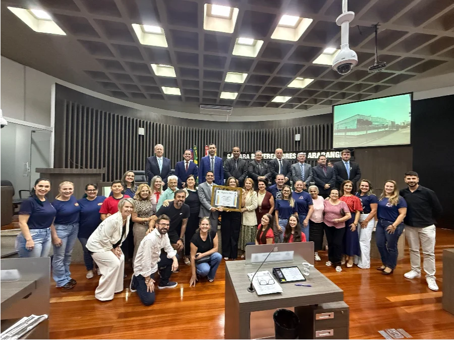 Araranguá homenageia 95 anos da Escola Maria Garcia Pessi Representantes da EEB Professora Maria Garcia Pessi e vereadores de Araranguá reunidos no plenário da Câmara segurando o quadro da Moção de Reconhecimento e Aplausos pelos 95 anos de fundação da escola.