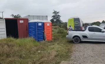 Obras da 4ª ponte de Araranguá avançam com novo canteiro Canteiro de obras inicial em Araranguá para a 4ª ponte, mostrando contêineres, banheiros químicos azul e laranja, caminhonetes Chevrolet Montana e outros veículos da equipe de engenharia.