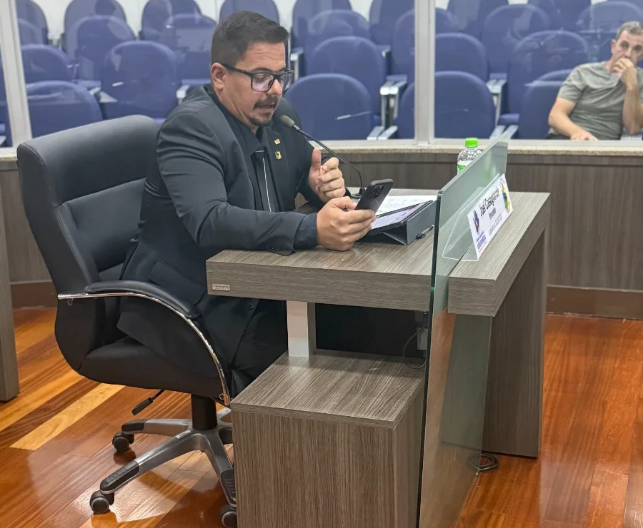 Vereador Joel Casagrande em sessão na Câmara de Vereadores de Araranguá, utilizando celular e tablet durante a aprovação do anteprojeto de lei para zeladoria urbana por MEIs.