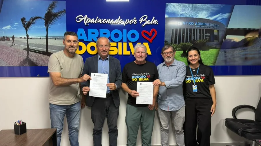 Prefeito Jorge Luiz Freitas e a secretária Manoella Porto recebem documento de recurso de R$ 200 mil para a saúde pública de Balneário Arroio do Silva, ao lado do vereador Elvio Zocche e representantes políticos.