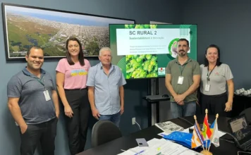 Arroio do Silva recebe novo projeto para setor rural Representantes da Epagri, o prefeito Jorge Luiz Freitas e a secretária Itaionara Recco durante reunião na Prefeitura de Balneário Arroio do Silva. Ao fundo, uma tela exibe o projeto SC Rural 2 com os dizeres Sustentabilidade e Inovação, destacando o planejamento para o setor rural e pesqueiro do município.