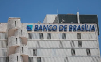 BRB estuda fechamento de agências e corte de despesas Fachada do prédio do Banco de Brasília (BRB) com letreiro azul em destaque sob céu limpo. A instituição financeira analisa um plano de redução de despesas que inclui o fechamento de agências e cortes de gastos operacionais.