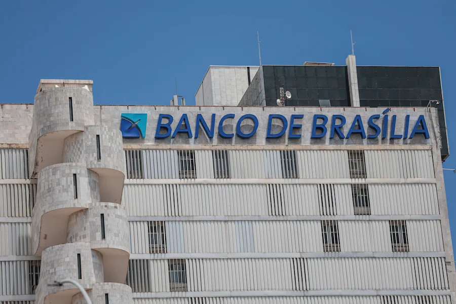 Fachada do prédio do Banco de Brasília (BRB) com letreiro azul em destaque sob céu limpo. A instituição financeira analisa um plano de redução de despesas que inclui o fechamento de agências e cortes de gastos operacionais.
