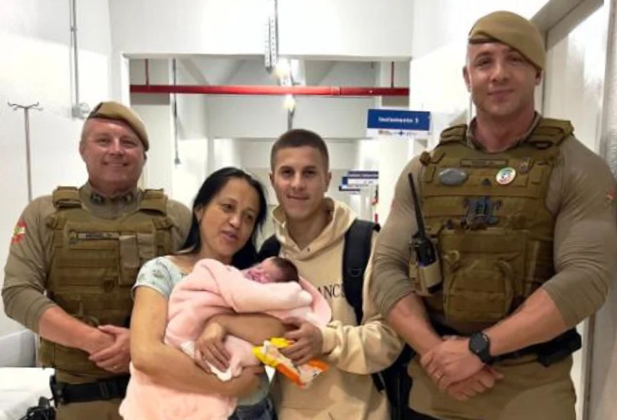Policiais militares de Maracajá posam ao lado de mãe e pai segurando bebê de 8 dias salvo após engasgamento no Hospital Regional de Araranguá.