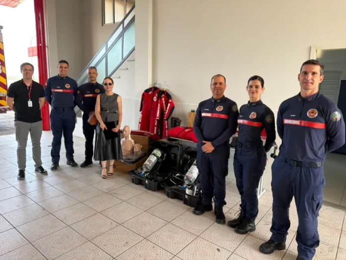 Bombeiros de Forquilhinha recebem R$ 65 mil em equipamentos Entrega simbólica de novos equipamentos operacionais e de prevenção para o Corpo de Bombeiros de Forquilhinha (CBMSC) em parceria com o MPSC. A promotora de Justiça Rafaela Póvoas Cardozo Lehmann e oficiais posam com os materiais doados, incluindo manequins de RCP, Equipamentos de Proteção Respiratória (EPRs), capacetes e roupas de neoprene, no interior de um quartel.