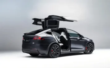 Brasileiro de SC é o 1º a consertar bateria de Tesla no país Tesla Model X preto com portas Falcon abertas, ilustrando o modelo de veículo elétrico que recebeu o primeiro conserto de bateria Tesla no Brasil, realizado em Araranguá.