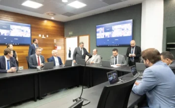 CCJ aprova admissibilidade da MP de salários dos professores Deputados reunidos em sessão extraordinária da CCJ em mesa redonda com notebooks e telas de videoconferência para votação da MP 269/2026 sobre a descompactação da tabela salarial dos professores estaduais.