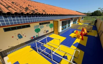 CEI de Santa Rosa do Sul instala novos pisos para crianças Área externa do CEI Vovó Leoncina em Santa Rosa do Sul exibindo a instalação de piso modular colorido nas cores azul e amarelo, com brinquedos de parquinho e estrutura pedagógica de PVC para atividades infantis.