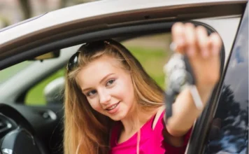 CNH para menores: Câmara discute redução da idade mínima Jovem loira sorrindo no banco do motorista de um carro, estendendo as chaves pela janela. Cena ilustrativa sobre o debate de redução da idade mínima para CNH.