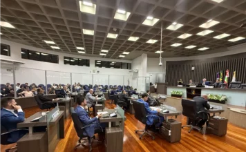 Câmara de Araranguá aprova reajuste de 4,2% para servidores Sessão ordinária na Câmara de Vereadores de Araranguá para votação do reajuste salarial de 4,2% dos servidores municipais. A imagem mostra parlamentares sentados em suas bancadas no plenário e público acompanhando a sessão ao fundo.
