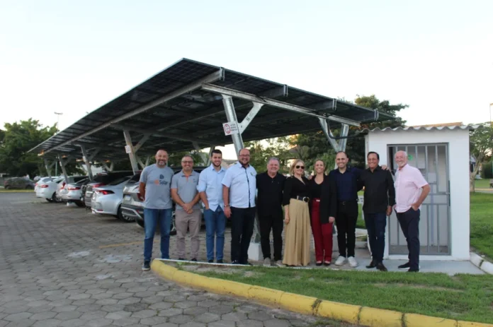 Câmara de Forquilhinha investe em energia solar e economia Autoridades e vereadores de Forquilhinha em frente à nova usina solar modelo carport instalada no estacionamento da Câmara Municipal. A estrutura metálica sustenta painéis solares fotovoltaicos sobre as vagas de veículos para geração de energia limpa e sustentável.