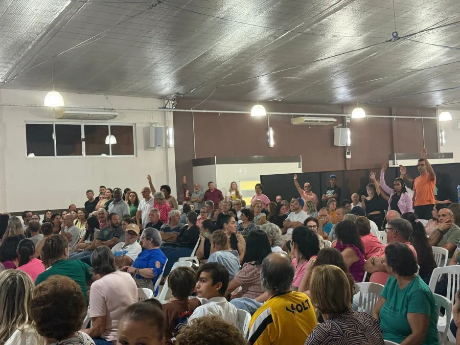 Moradores de Cocal do Sul reunidos em audiência pública no bairro Jardim Itália, com algumas pessoas levantando as mãos para votar o fechamento da Rua Raul Pompeia e o avanço da obra da Rua Coberta.