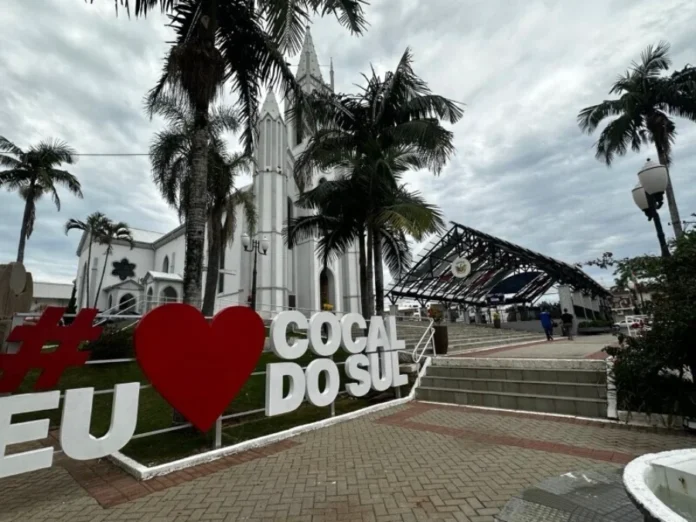 Cocal do Sul convoca interessados no programa Adote uma Praça Vista da praça central de Cocal do Sul com letreiro turístico "Eu Amo Cocal do Sul" em destaque, tendo a Igreja Matriz ao fundo. A imagem exemplifica um dos espaços públicos que podem ser beneficiados pelo programa Adote uma Praça para manutenção e melhorias.