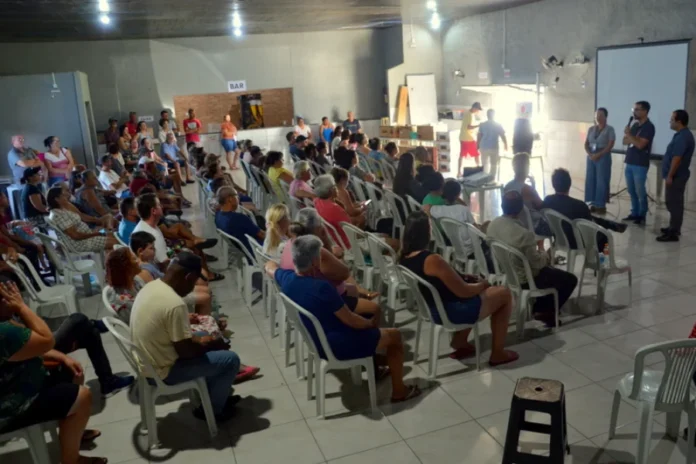 Colônia Z33 recebe equipamentos e debate crédito no Rincão Mais de 200 pescadores artesanais assistem a uma reunião da Colônia Z33 em Balneário Rincão, SC, onde estão sendo apresentados novos equipamentos multimídia. No palco, oradores falam diante de uma tela de projeção. O público está sentado em cadeiras de plástico. Ao fundo, um balcão com letreiro BAR.