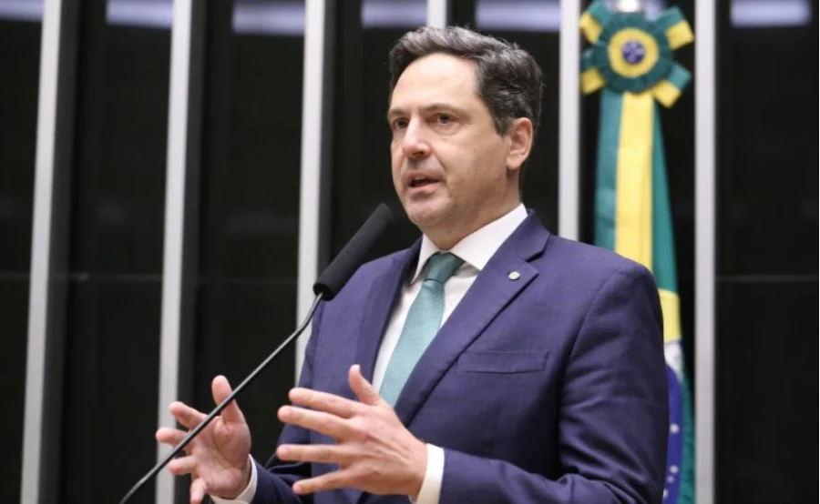 Deputado Federal Luiz Philippe de Orleans e Bragança discursando no plenário da Câmara dos Deputados. Ele é o relator da proposta aprovada que classifica o PCC e o Comando Vermelho como organizações terroristas no Brasil. Imagem foca no deputado falando ao microfone, com a bandeira do Brasil ao fundo.