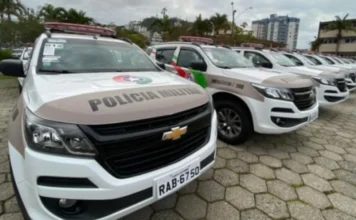Confusão em família termina em prisão por racismo em Turvo Fileira de viaturas da Polícia Militar de Santa Catarina (PMSC) estacionadas, com destaque para os veículos brancos e beges com o emblema da corporação. Foto ideal para ilustrar operações policiais, prisões e segurança pública em Santa Catarina.