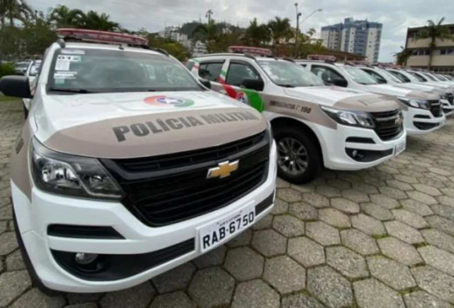 Confusão em família termina em prisão por racismo em Turvo Fileira de viaturas da Polícia Militar de Santa Catarina (PMSC) estacionadas, com destaque para os veículos brancos e beges com o emblema da corporação. Foto ideal para ilustrar operações policiais, prisões e segurança pública em Santa Catarina.