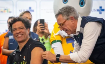 Copa 2026: Saúde lança campanha de vacina contra sarampo Ministro da Saúde Alexandre Padilha aplica vacina contra o sarampo no ex-jogador Raí durante lançamento da campanha "Vacinar é muito Brasil" para a Copa do Mundo 2026, com o personagem Zé Gotinha ao fundo.