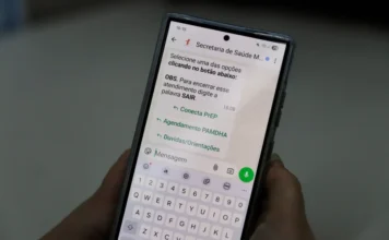 Criciúma lança teleatendimento para prevenção ao HIV Pessoa segurando smartphone com a tela do WhatsApp aberta no serviço Conecta PrEP da Secretaria de Saúde de Criciúma. Na tela, aparecem opções de menu para agendamento e orientações sobre prevenção ao HIV via teleatendimento.
