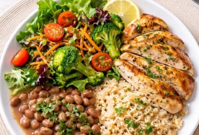Emagrecer sem ficar fraco, é possível sim! Prato de alimentação saudável e equilibrada contendo peito de frango grelhado fatiado, arroz integral, feijão e salada colorida com brócolis, alface e tomates cereja. Foto foca no conceito de déficit calórico com densidade nutricional.